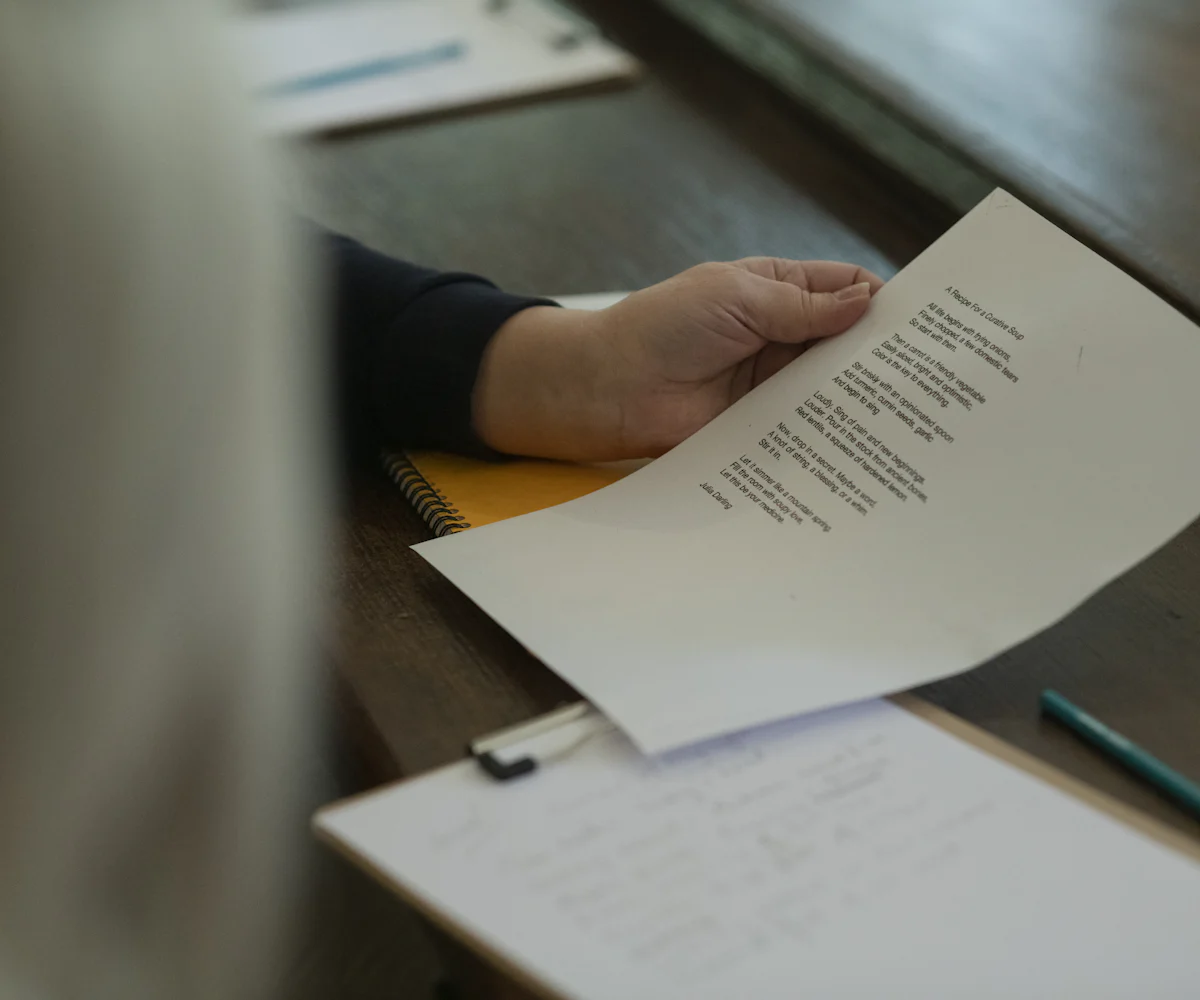 Mano sujetando una carta impresa sobre un escritorio de madera