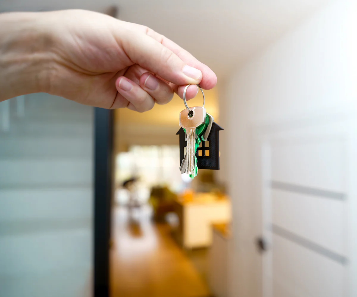 Mano sosteniendo las llaves de una vivienda en el recibidor