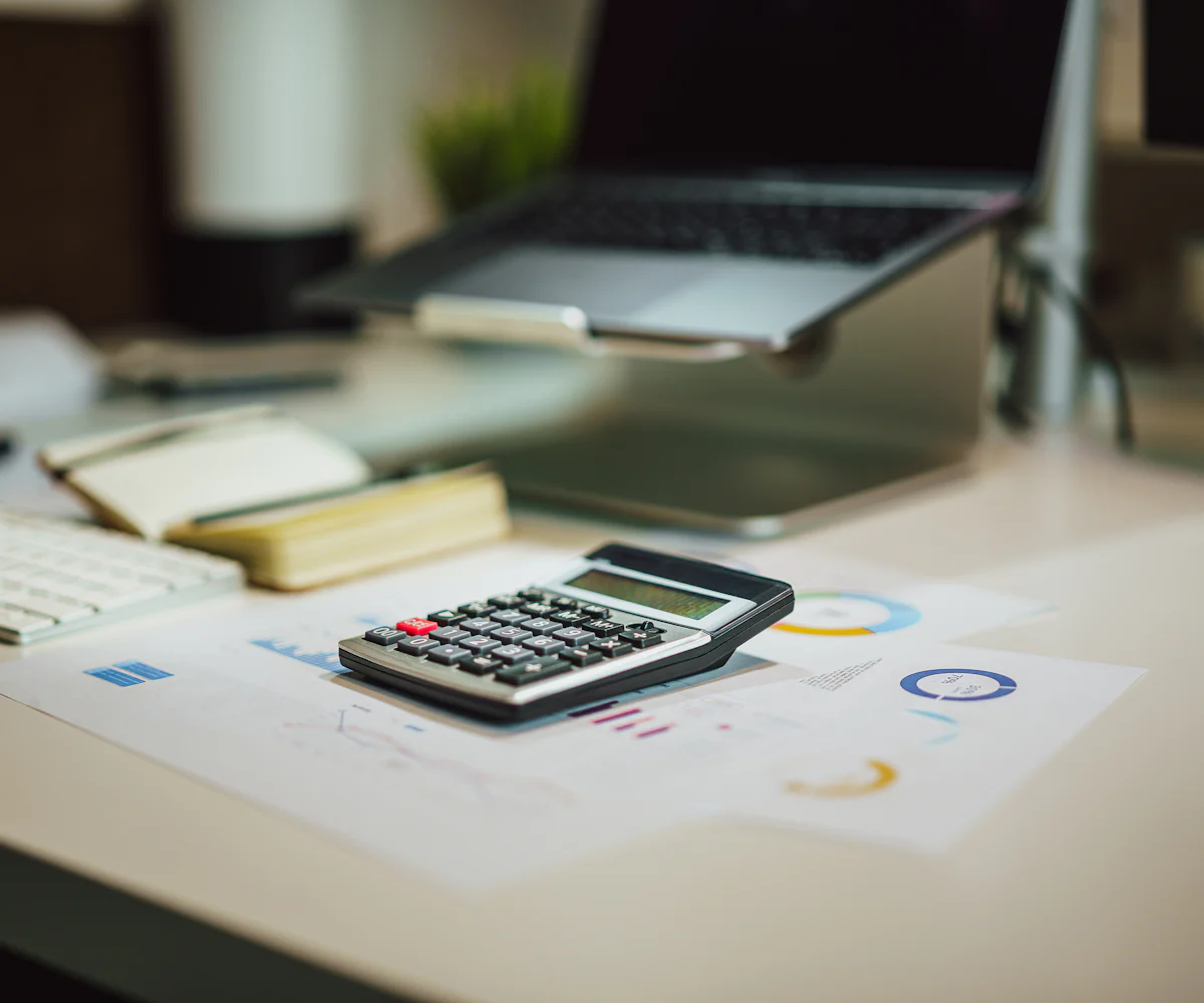 Calculadora sobre documentos con cifras y gráficos en un escritorio de oficina